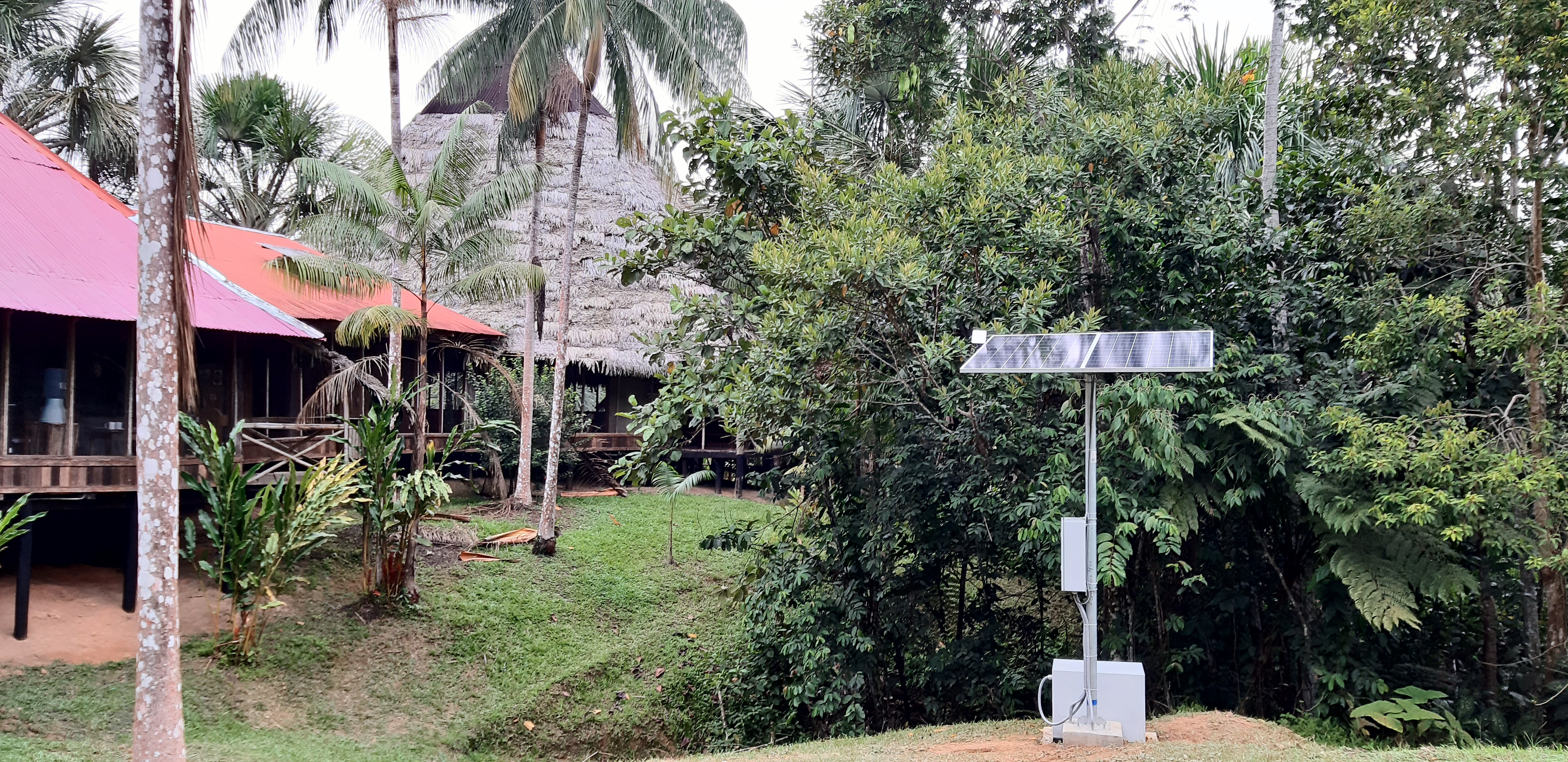 Panel solar y gabinete de equipos instalados junto a las cabañas de un albergue en plena selva amazónica